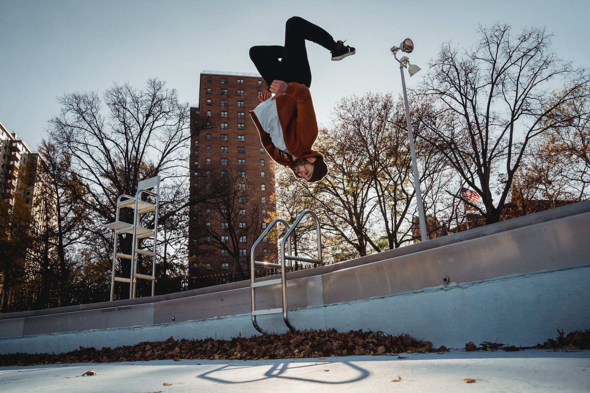 sportsman performing back flip against city park